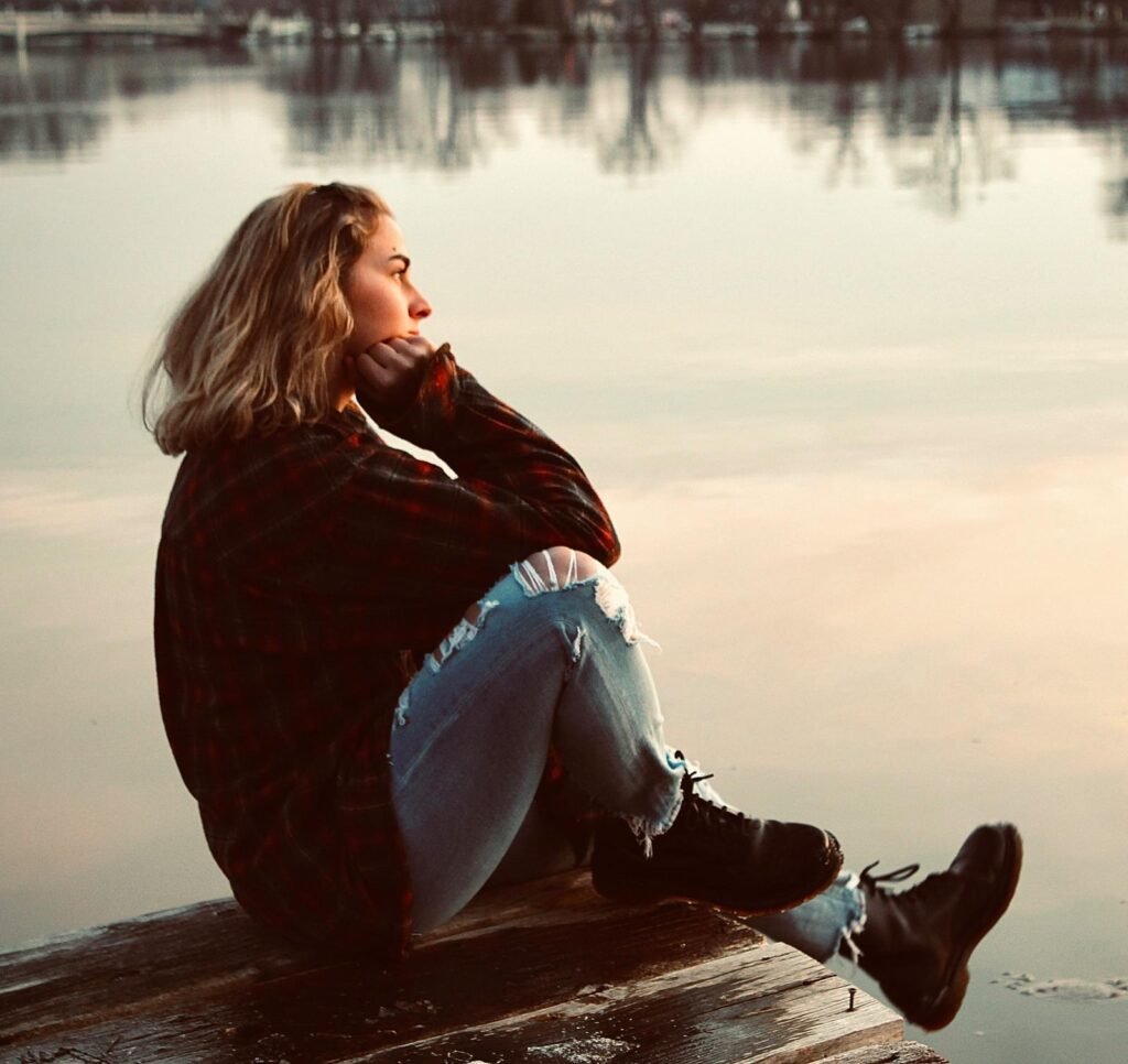 Woman sitting quietly by a lake and reflecting